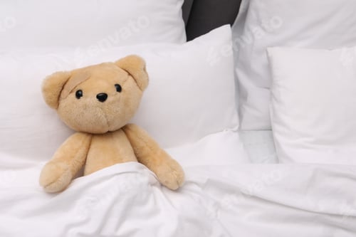Preview: Toy cute bear with sticking plaster under blanket in bed