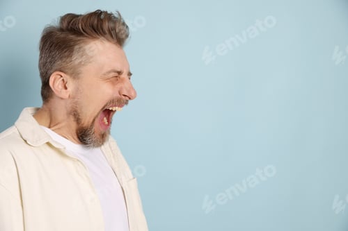 Preview: Resentful man screaming on light blue background. Space for text