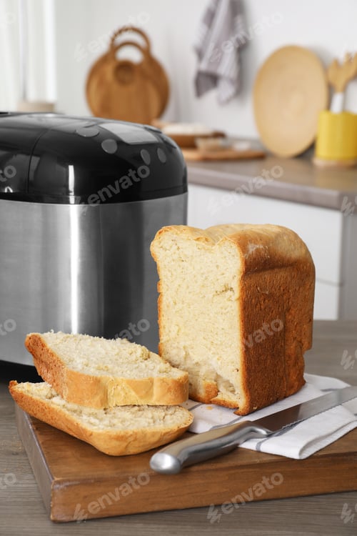 Preview: Breadmaker and cut homemade bread on wooden table in kitchen