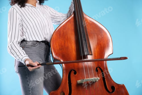 Preview: Woman playing double bass on light blue background, closeup