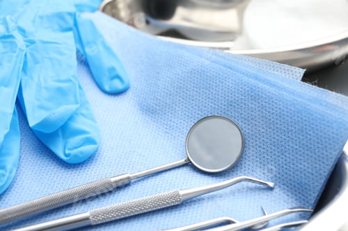 Preview: Different dental tools, medical napkin and rubber glove on table, closeup