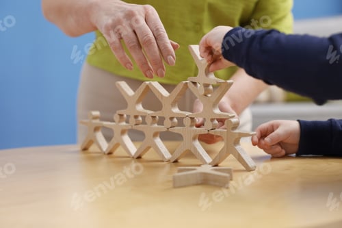 Preview: Nanny and cute little boy playing with wooden human figures at table indoors, closeup