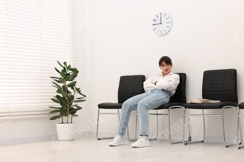 Preview: Woman sitting on chair and waiting for appointment indoors