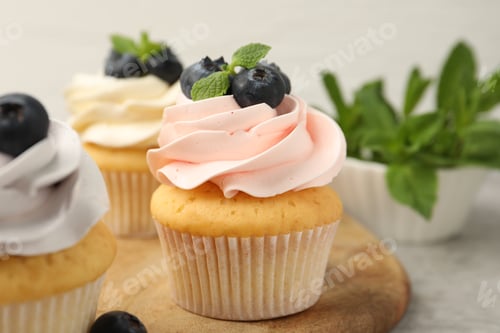 Preview: Yummy cupcakes with blueberries and mint on grey table, closeup