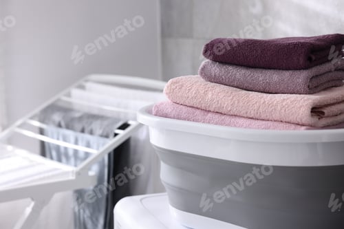 Preview: Many clean towels in laundry basket on washing machine indoors, closeup. Space for text
