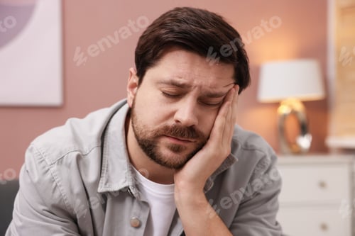 Preview: Unhappy man feeling extreme fatigue at home
