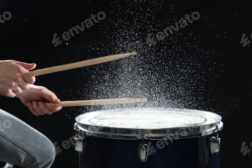 Preview: Man with drumsticks playing drum on black background, closeup