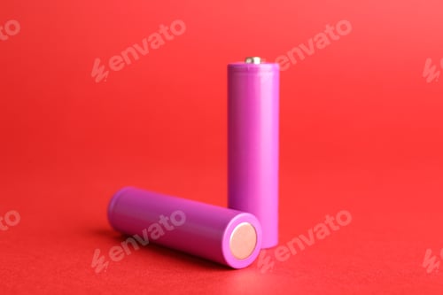 Preview: Two alkaline batteries on red background, closeup