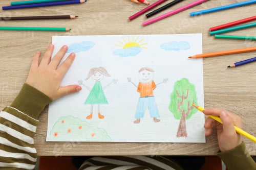 Preview: Little boy drawing with pencil at wooden table, top view