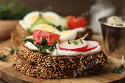 Preview: Tasty sandwiches with cream cheese, cucumbers, tomatoes, eggs and microgreens on wooden table, close