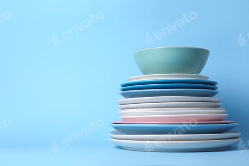 Preview: Clean dishes on light blue background, closeup. Space for text