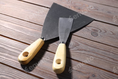 Preview: Putty knives on wooden table, closeup. Construction tool