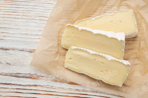 Preview: Slices of delicious brie cheese on color wooden table, top view. Space for text