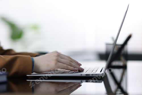 Preview: Woman working with laptop at mirror table indoors, closeup