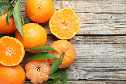 Preview: Fresh tangerines and green leaves on wooden table, flat lay. Space for text
