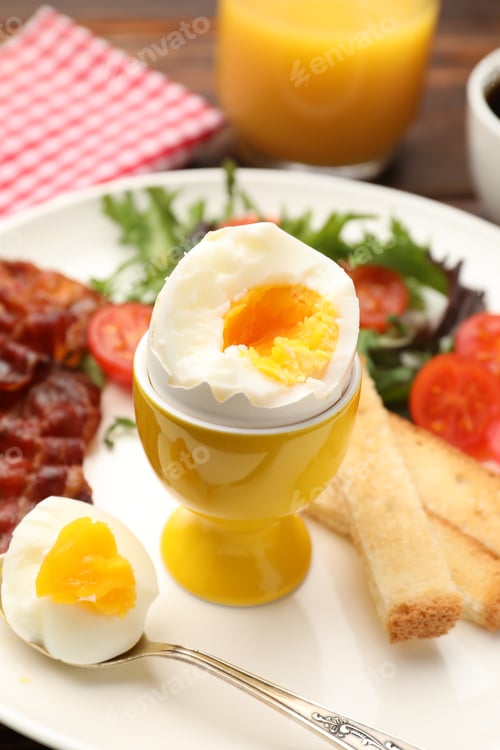 Preview: Tasty breakfast with hard boiled egg and bacon served on table, closeup