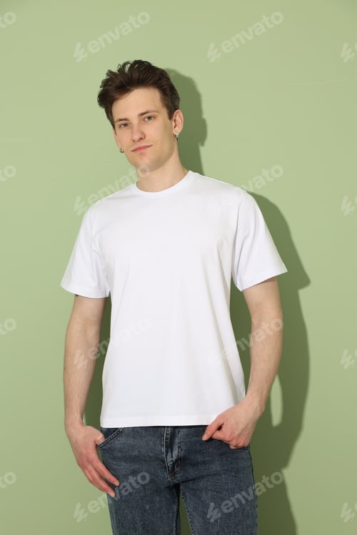 Preview: Handsome young man wearing blank white t-shirt on light green background. Mockup for design