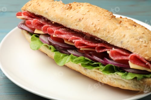 Preview: Tasty baguette sandwich with salami, cheese and vegetables served on light blue wooden table, closeu