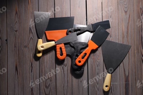 Preview: Putty knives on wooden table, flat lay. Construction tool