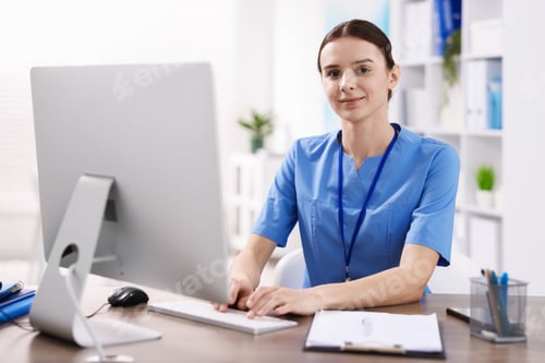 Preview: Medical assistant working at desk in clinic