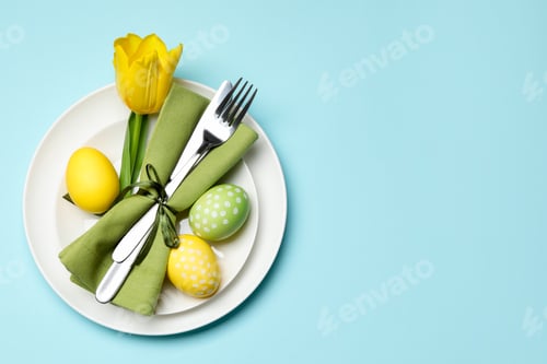 Preview: Easter celebration. Festive table setting with tulip flower and painted eggs on light blue backgroun
