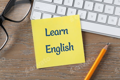 Preview: Paper note with phrase Learn English, computer keyboard, glasses and pencil on wooden background, to