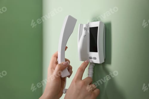 Preview: Woman with handset pressing button on intercom panel indoors, closeup