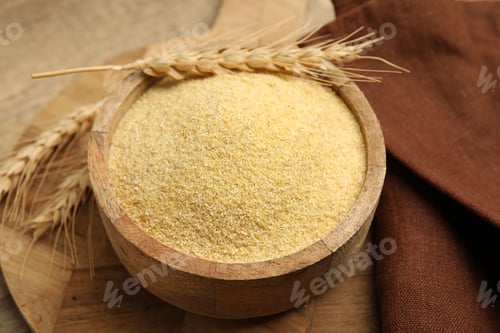 Preview: Raw semolina in bowl with spikes on wooden table, closeup