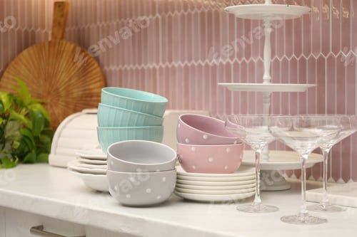 Preview: Set of clean plates, glasses and bowls on white marble countertop in kitchen, closeup