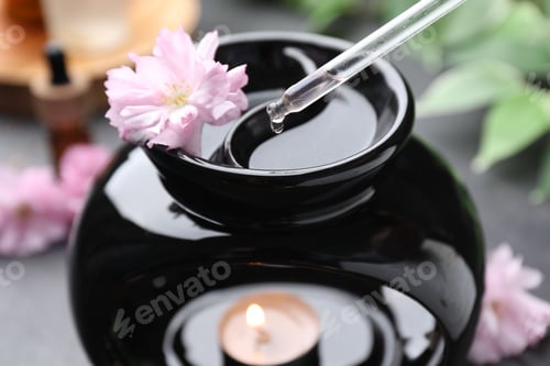 Preview: Aromatherapy. Dripping essential oil into aroma lamp on black table, closeup