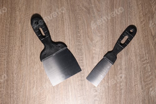 Preview: Putty knives on wooden table, flat lay. Construction tool