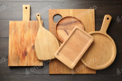 Preview: Different cutting boards and trays on dark wooden table, flat lay