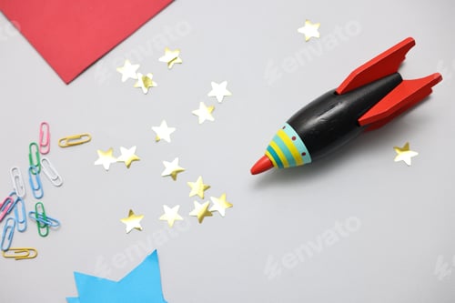 Preview: Toy rocket and art materials on light table, flat lay