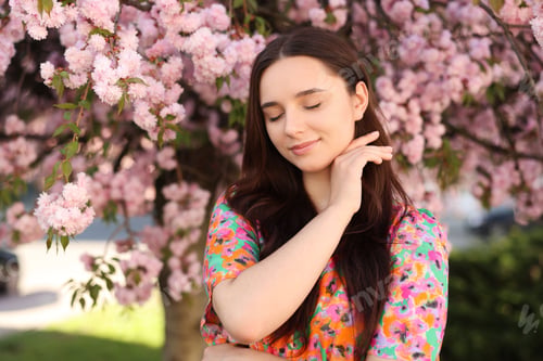Preview: Beautiful woman near blossoming tree on spring day
