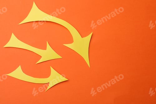 Preview: Yellow paper arrows on orange background, flat lay. Space for text