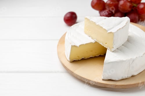 Preview: Cut delicious brie cheese and grapes on white wooden table, closeup. Space for text