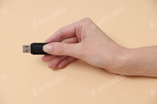Preview: Woman with USB flash drive on beige background, closeup