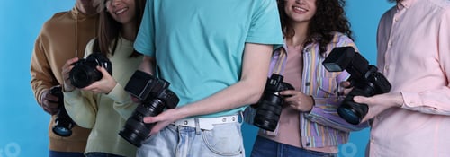 Preview: Group of photographers with professional cameras against light blue background