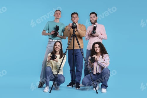 Preview: Group of photographers with professional cameras against light blue background