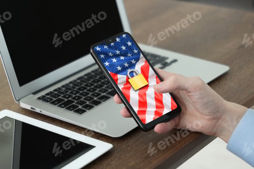 Preview: Man using mobile phone with paddle lock and USA flag on screen at table, closeup. Visa application