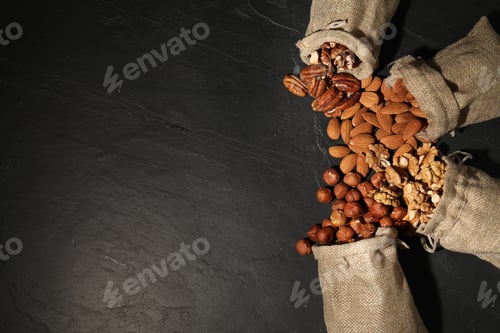 Preview: Different types of nuts on black table, flat lay. Space for text