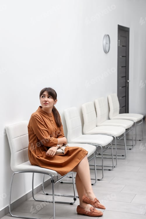 Vista previa: Woman sitting on chair and waiting for appointment indoors