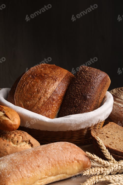 Preview: Different types of bread and wheat spikes on wooden table, closeup