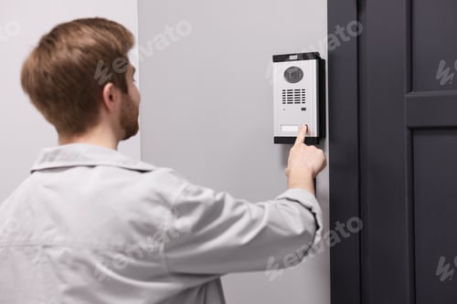 Preview: Man pressing button on intercom panel indoors