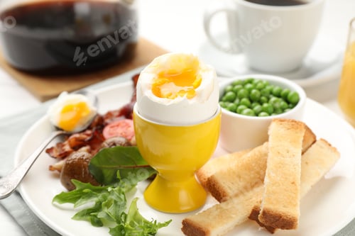 Preview: Tasty breakfast with soft boiled egg and bacon served on table, closeup
