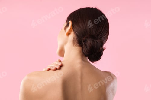 Preview: Beautiful woman touching her neck on pink background, back view