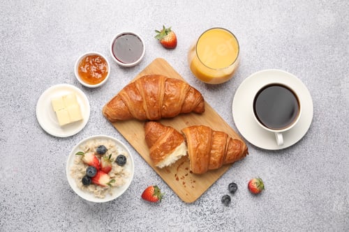 Preview: Yummy breakfast. Tasty croissants, jam, berries, oatmeal and drinks on light grey table, flat lay