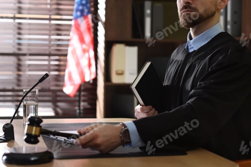 Preview: Portrait of judge in glasses striking gavel at table in office