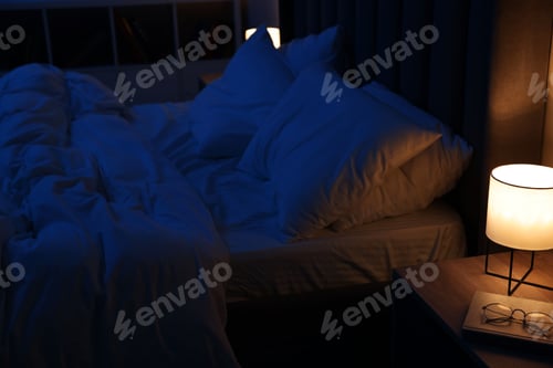 Preview: Nightlight, glasses and book on bedside table near bed indoors
