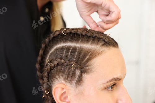 Preview: Hairstylist braiding teenage girl's hair in salon, closeup